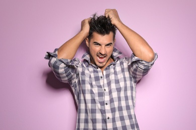 Photo of Young man with trendy hairstyle posing on color background