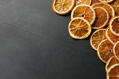 Photo of Dry orange slices on black table, above view. Space for text