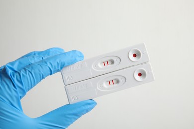 Photo of Doctor holding two disposable express tests for hepatitis on white background, closeup