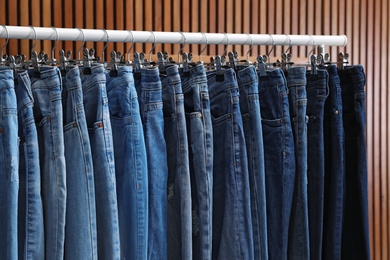Photo of Rack with different stylish jeans on wooden background