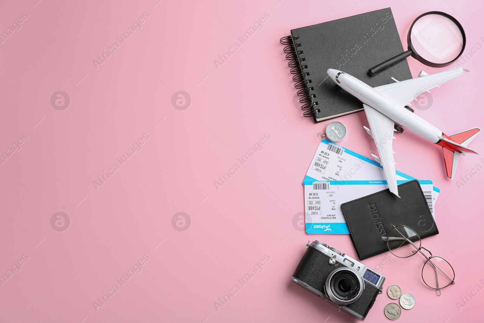 Photo of Flat lay composition with toy airplane and travel items on pink background. Space for text