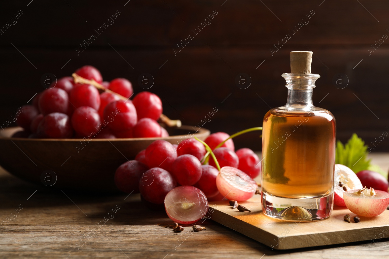 Photo of Bottle of natural grape seed oil on wooden table, space with text. Organic cosmetic