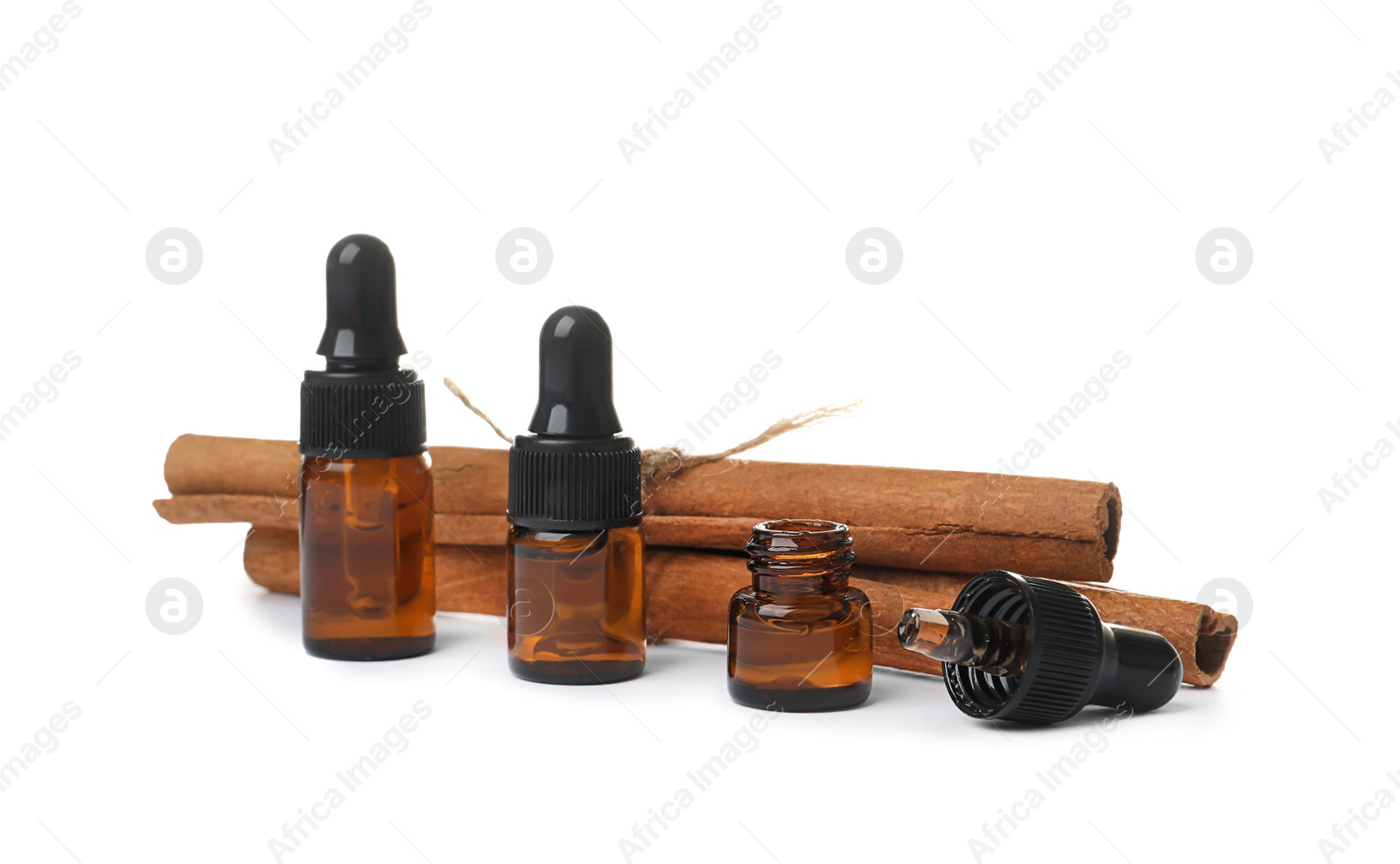 Photo of Bottles with cinnamon oil and sticks on white background