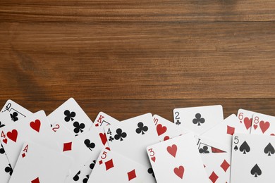 Photo of Playing cards on wooden table, flat lay. Space for text
