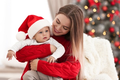 Photo of Happy mother with cute baby in room decorated for Christmas holiday