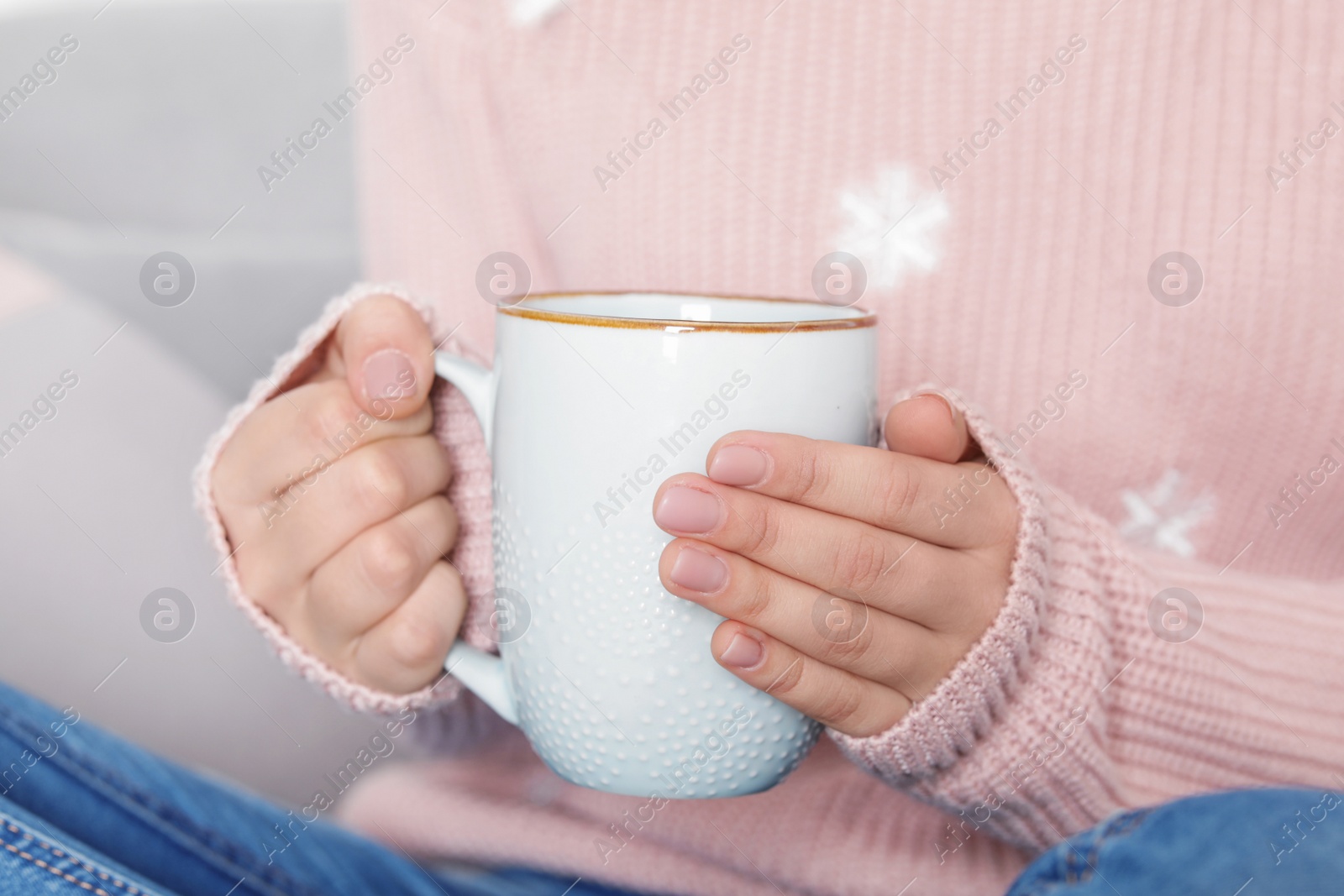 Photo of Young woman in warm sweater holding cup of hot drink, closeup