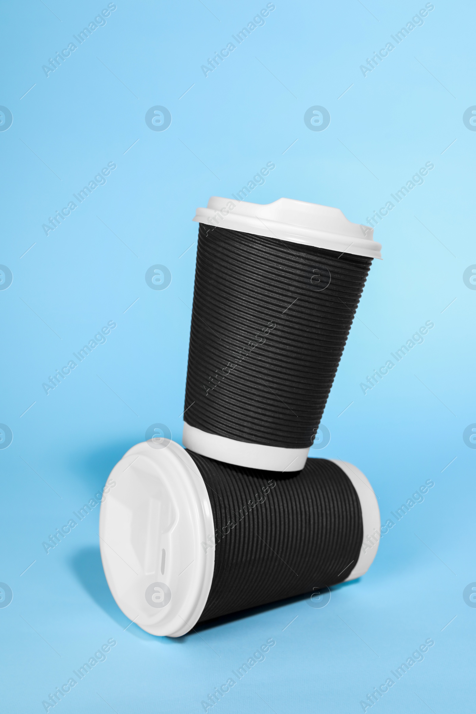 Photo of Paper cups with white lids on light blue background. Coffee to go