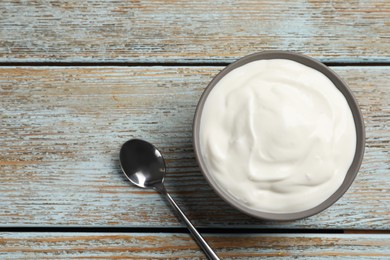 Photo of Ceramic bowl with delicious organic yogurt and spoon on wooden table, flat lay. Space for text