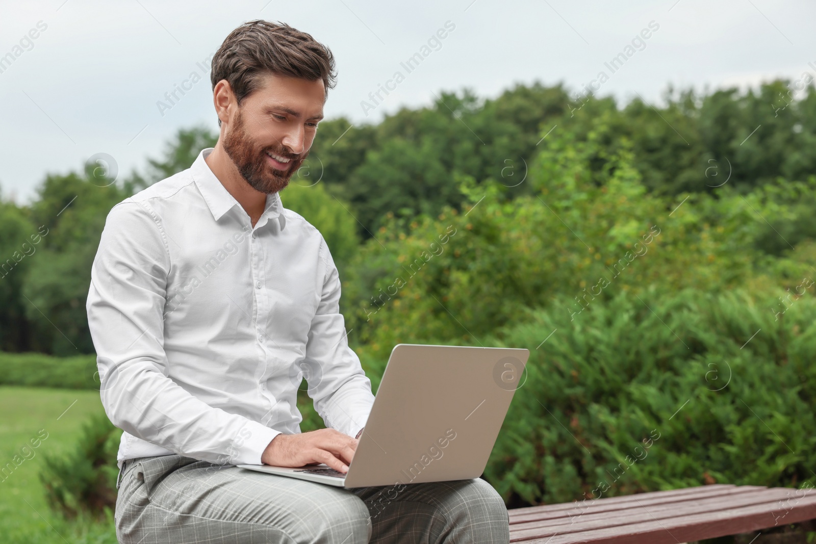 Photo of Handsome businessman with laptop on bench in park