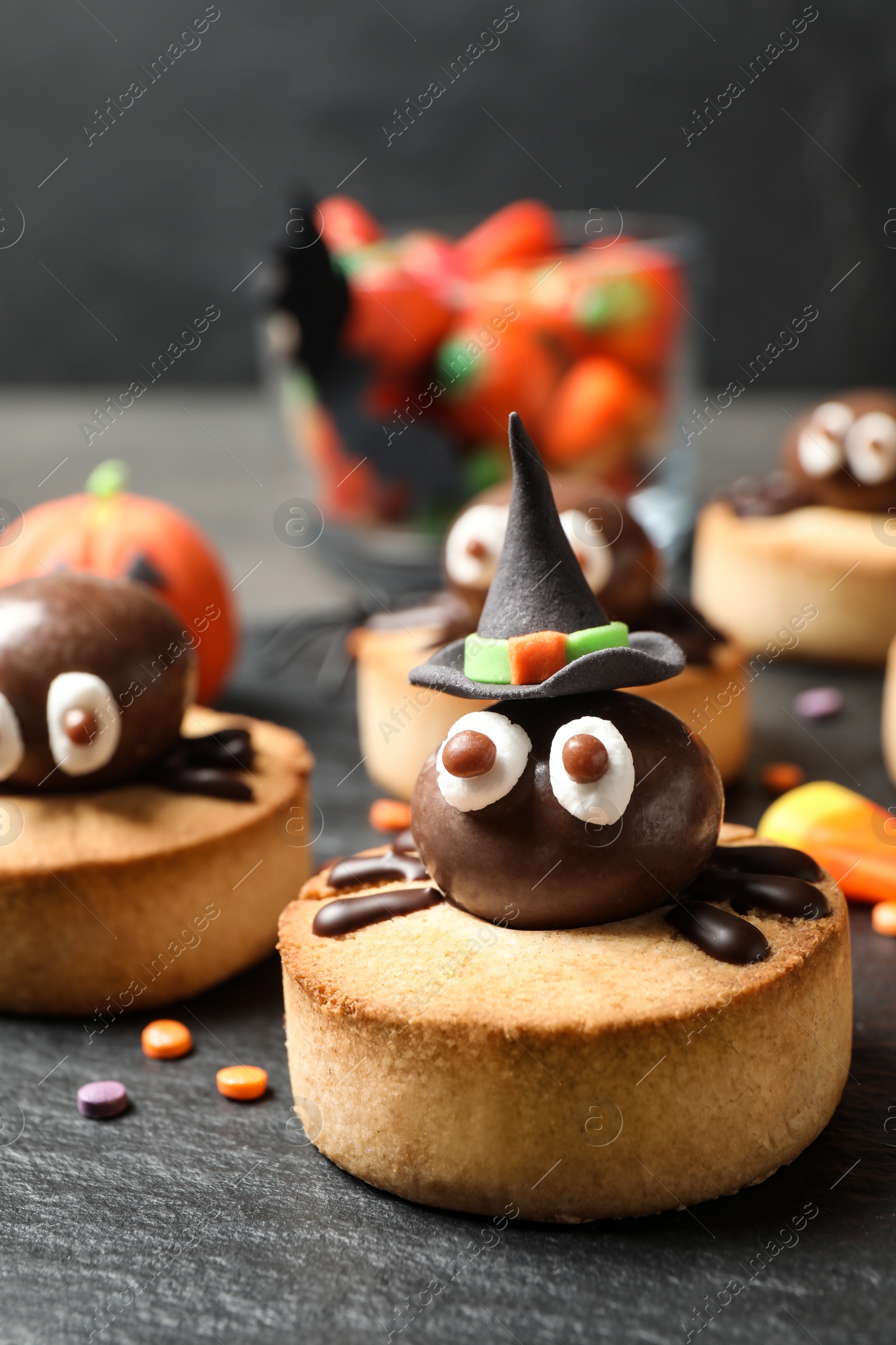 Photo of Delicious biscuits with chocolate spiders on slate plate, closeup. Halloween celebration