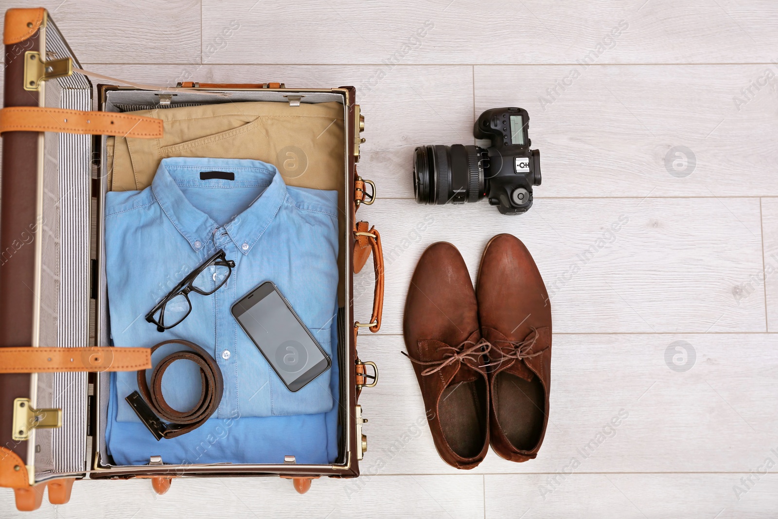 Photo of Packed suitcase on wooden background, top view. Space for text