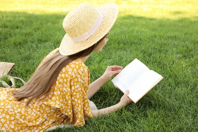 Photo of Young woman reading book on green grass