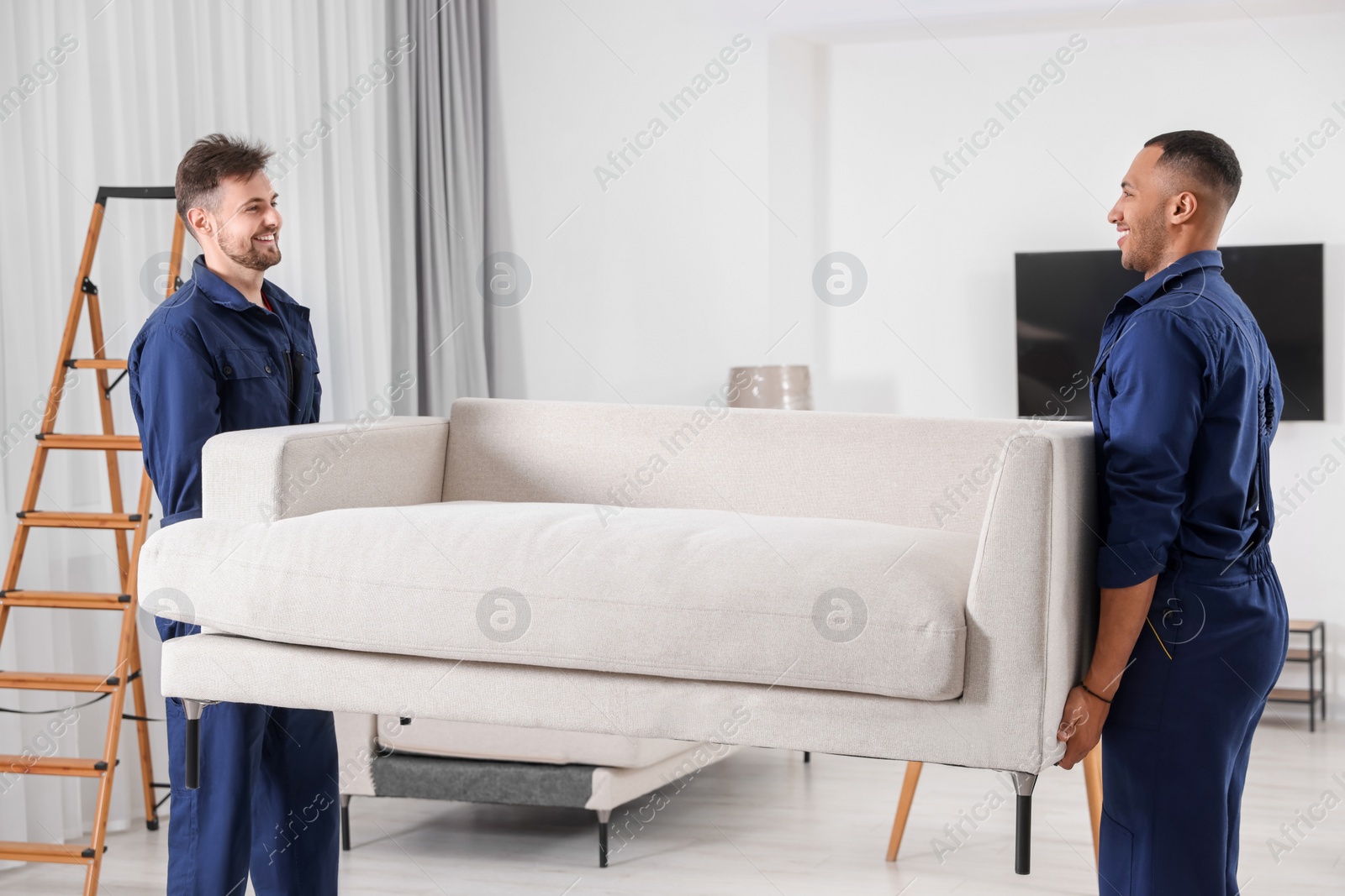 Photo of Male movers carrying sofa in new house