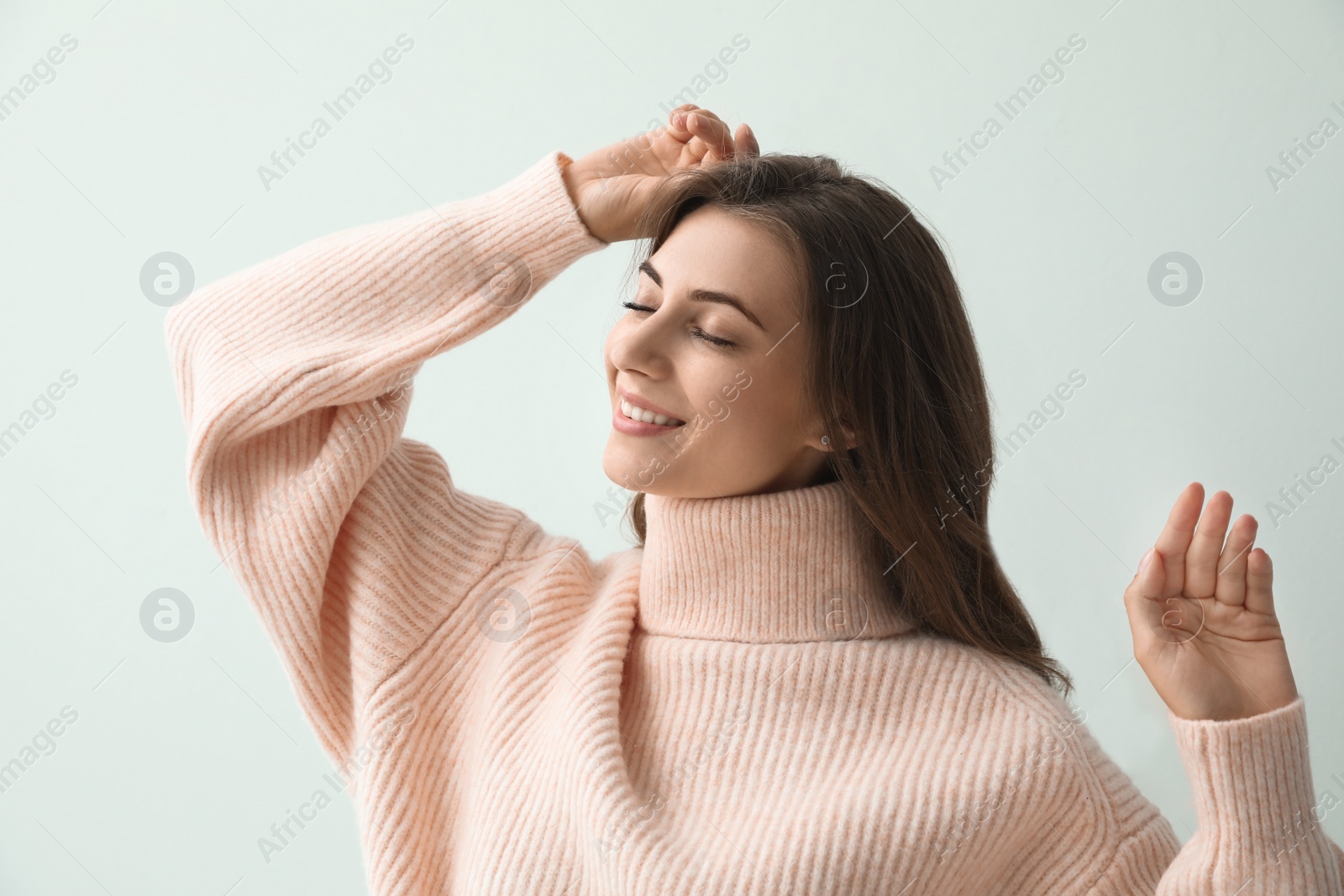 Photo of Beautiful young woman wearing warm pink sweater on light background