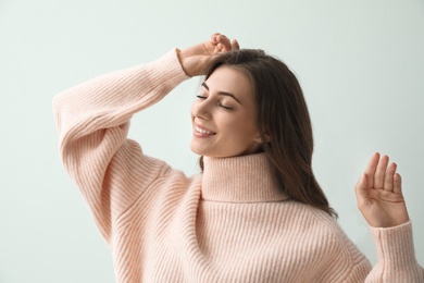 Beautiful young woman wearing warm pink sweater on light background