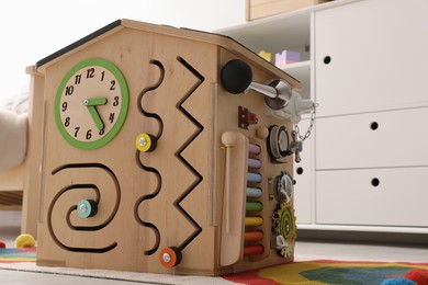 Photo of Busy board house on floor indoors. Baby sensory toy