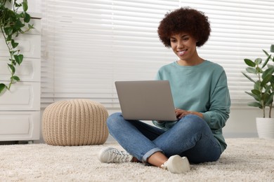 Photo of Beautiful young woman using laptop in room, space for text