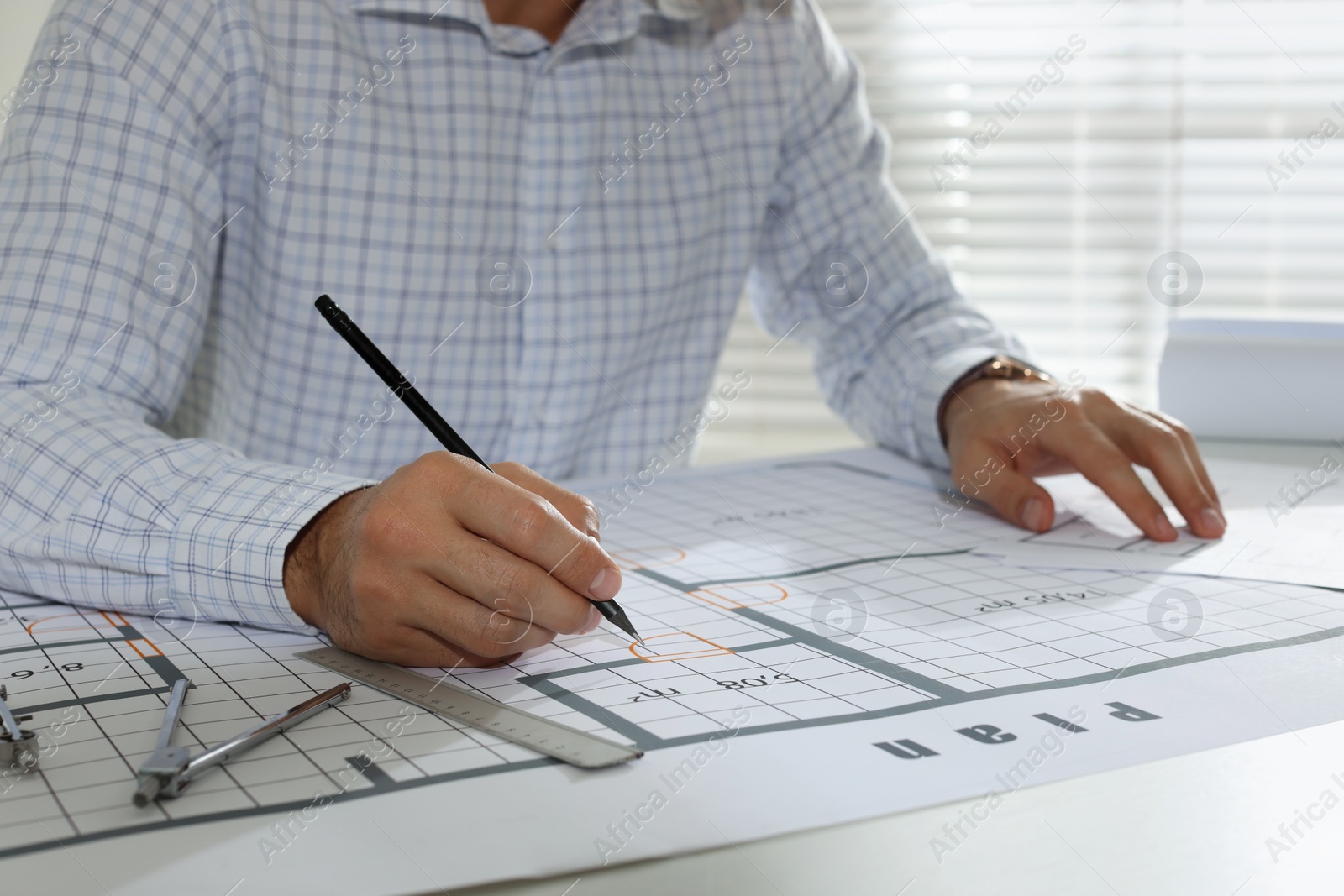 Photo of Architect working with construction drawings in office, closeup