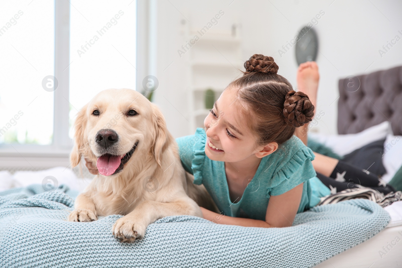 Photo of Cute little child with her pet on bed at home