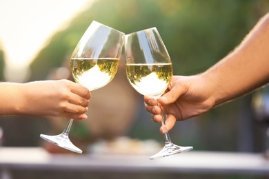 Photo of Couple with glasses of white wine outdoors, closeup