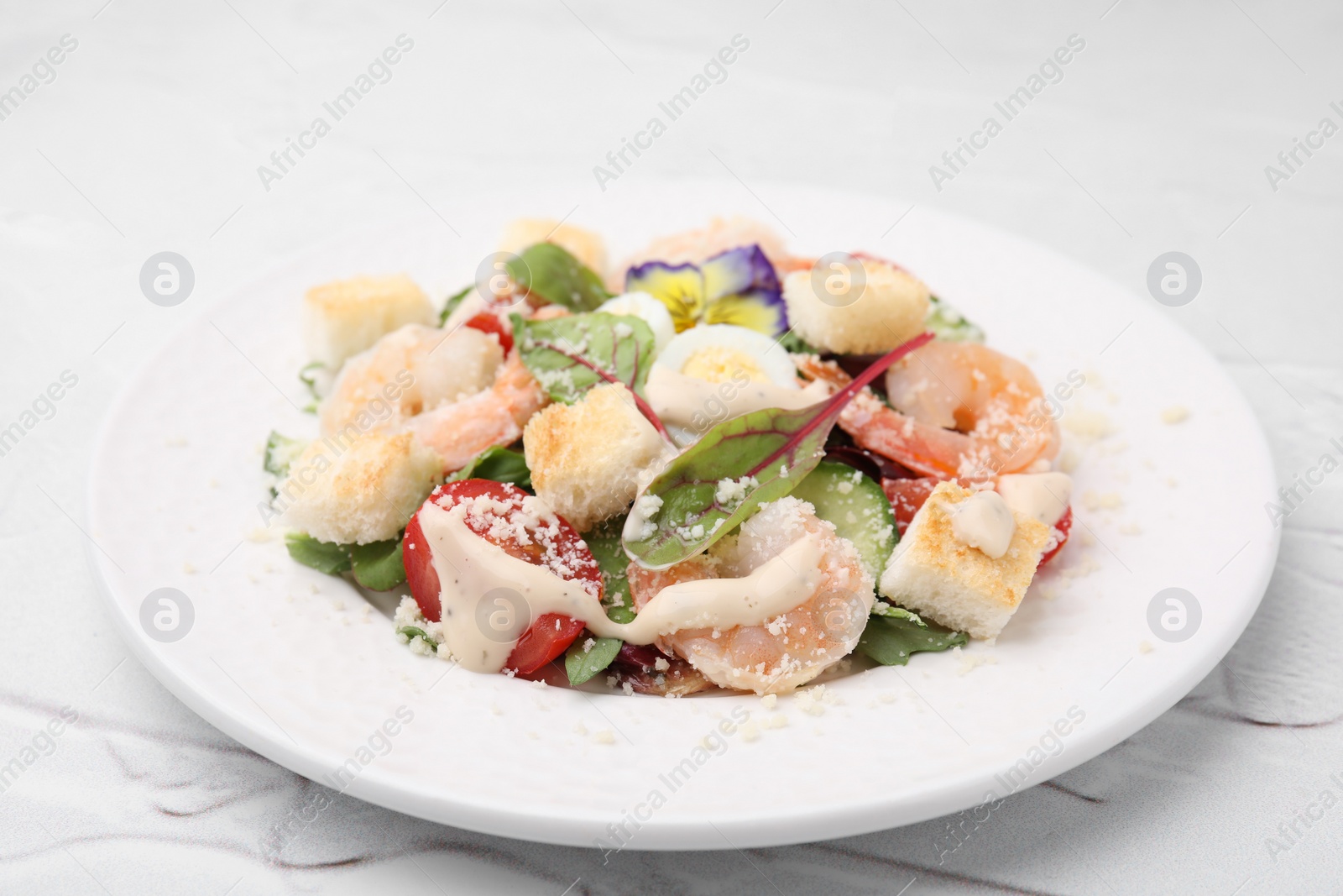 Photo of Delicious Caesar salad with shrimps on white table, closeup