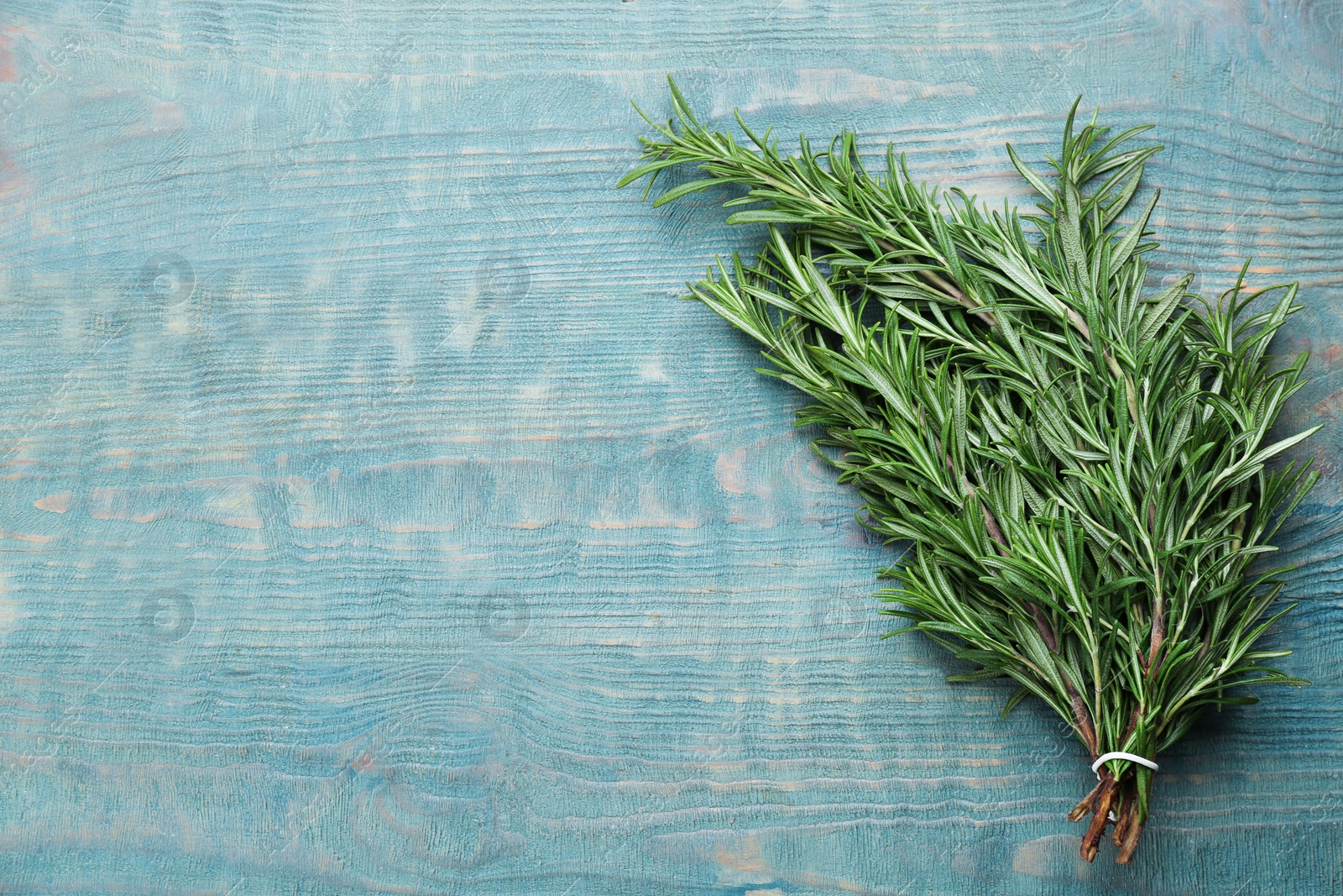 Photo of Bunch of fresh rosemary on light blue wooden table, top view. Space or text