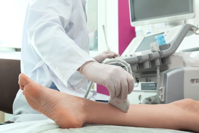 Photo of Doctor conducting ultrasound examination of patient's leg in clinic, closeup