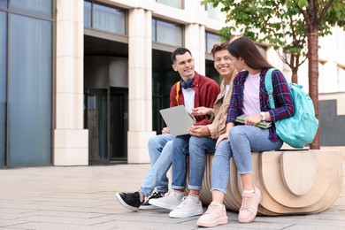 Photo of Happy young students with laptop learning together outdoors