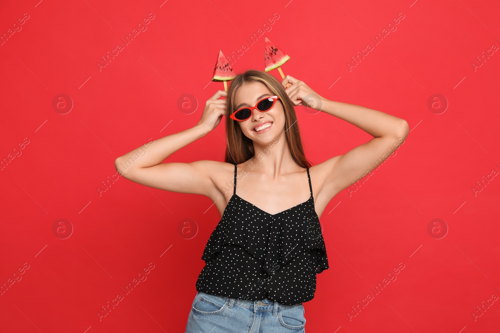 Photo of Beautiful girl with pieces of watermelon on red background