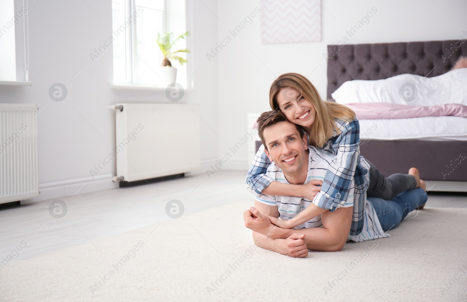 Photo of Lovely young couple lying on cozy carpet at home