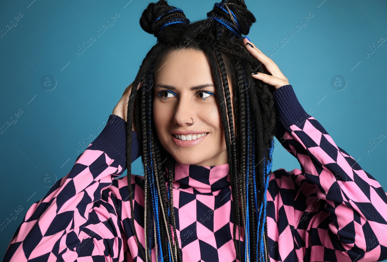 Photo of Beautiful young woman with nose piercing and dreadlocks on light blue background