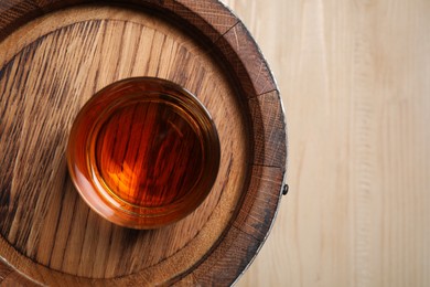 Wooden barrel and glass of tasty whiskey on table, top view. Space for text
