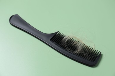 Photo of Comb with lost hair on green background