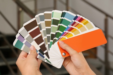 Photo of Female interior designer with color palette samples indoors, closeup