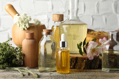 Aromatherapy. Different essential oils, herbs and flowers on wooden table