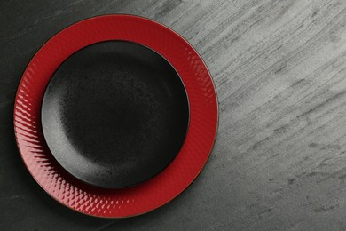 Photo of Beautiful ceramic plates on black table, top view. Space for text