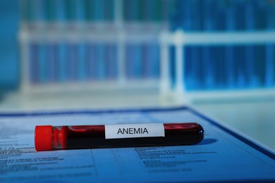 Photo of Tube with blood sample and label Anemia on laboratory test form, closeup. Space for text