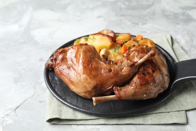 Photo of Tasty cooked rabbit meat with vegetables on light grey table