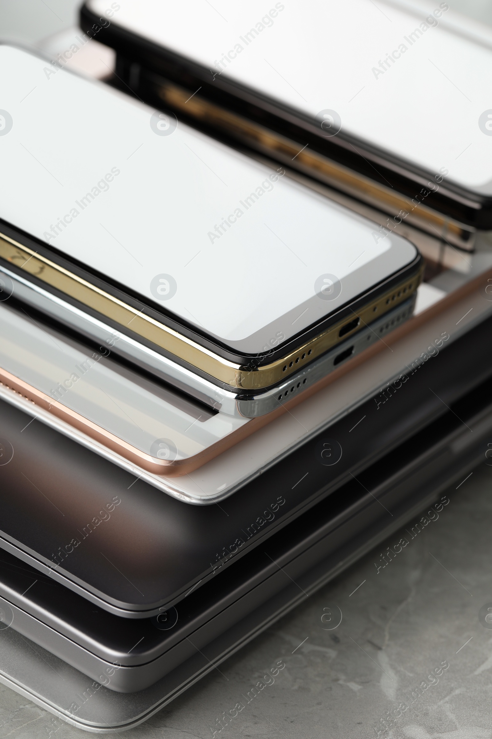 Photo of Stack of electronic devices on grey stone table, closeup