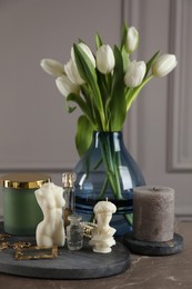 Photo of Beautiful sculptural candles, flowers and decor on grey table