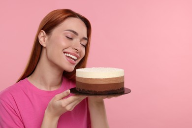 Young woman with tasty cake on pink background