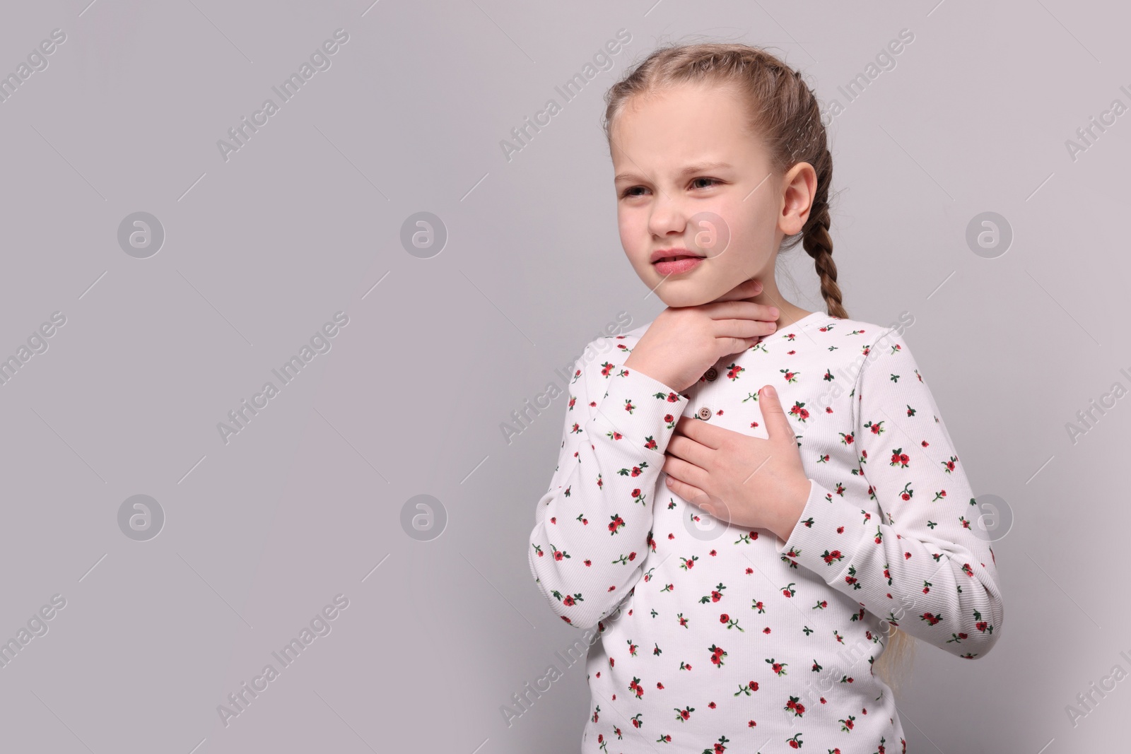 Photo of Girl suffering from sore throat on light grey background. Space for text