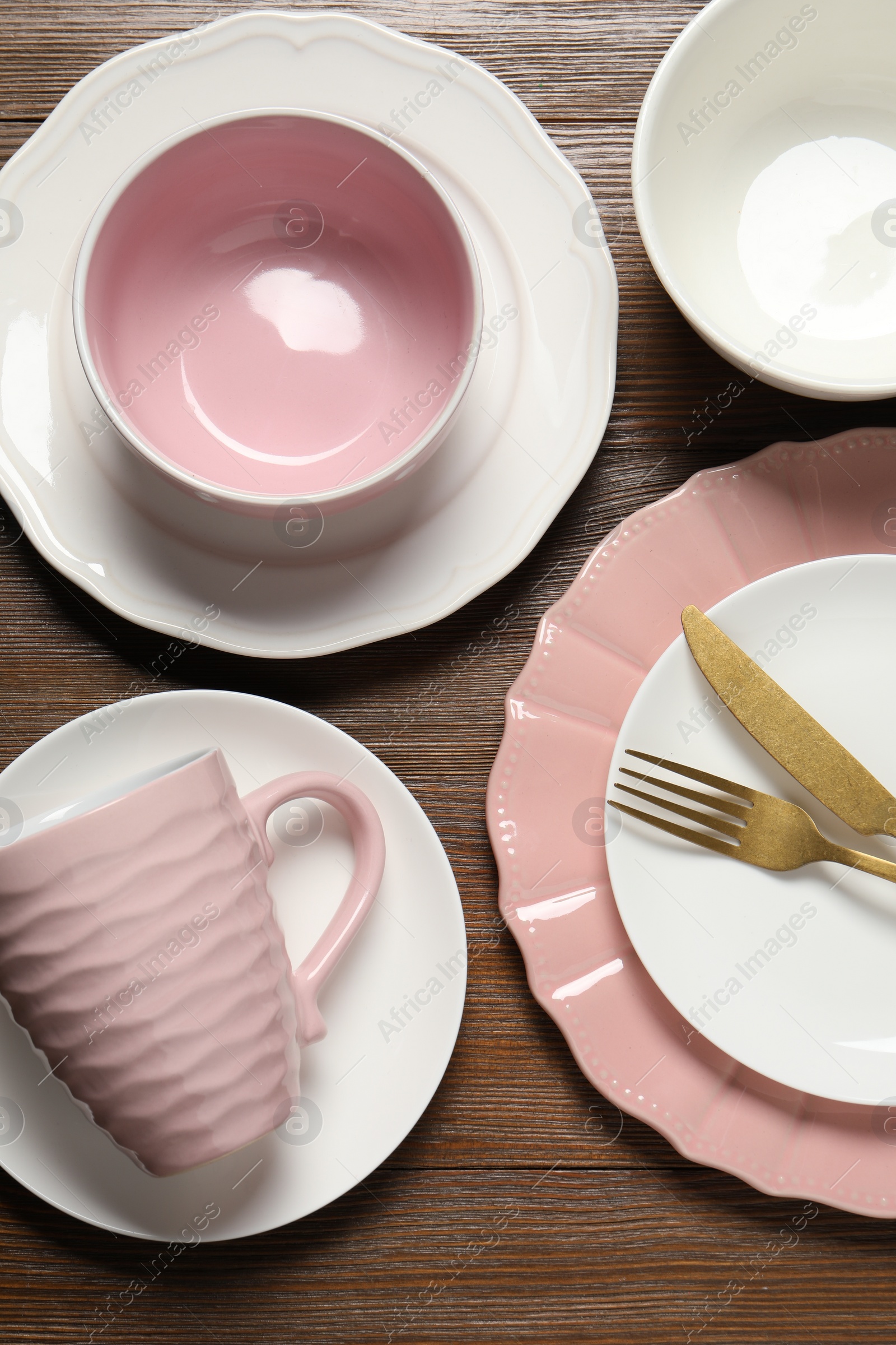 Photo of Beautiful ceramic dishware, cutlery and cup on wooden table, flat lay