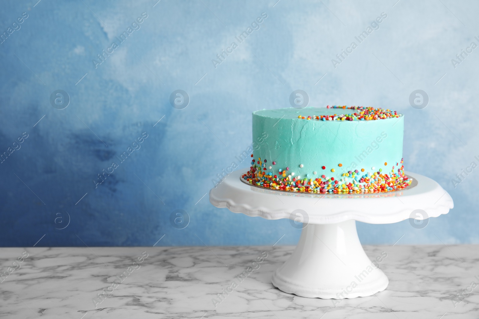 Photo of Fresh delicious birthday cake on stand against color background. Space for text