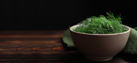 Image of Fresh dill in bowl on wooden table against black background. Banner design with space for text