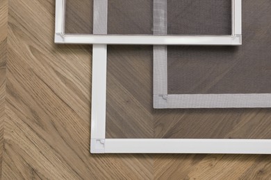 Set of window screens on wooden floor, flat lay