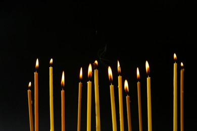 Photo of Burning candles on black background. Symbol of sorrow