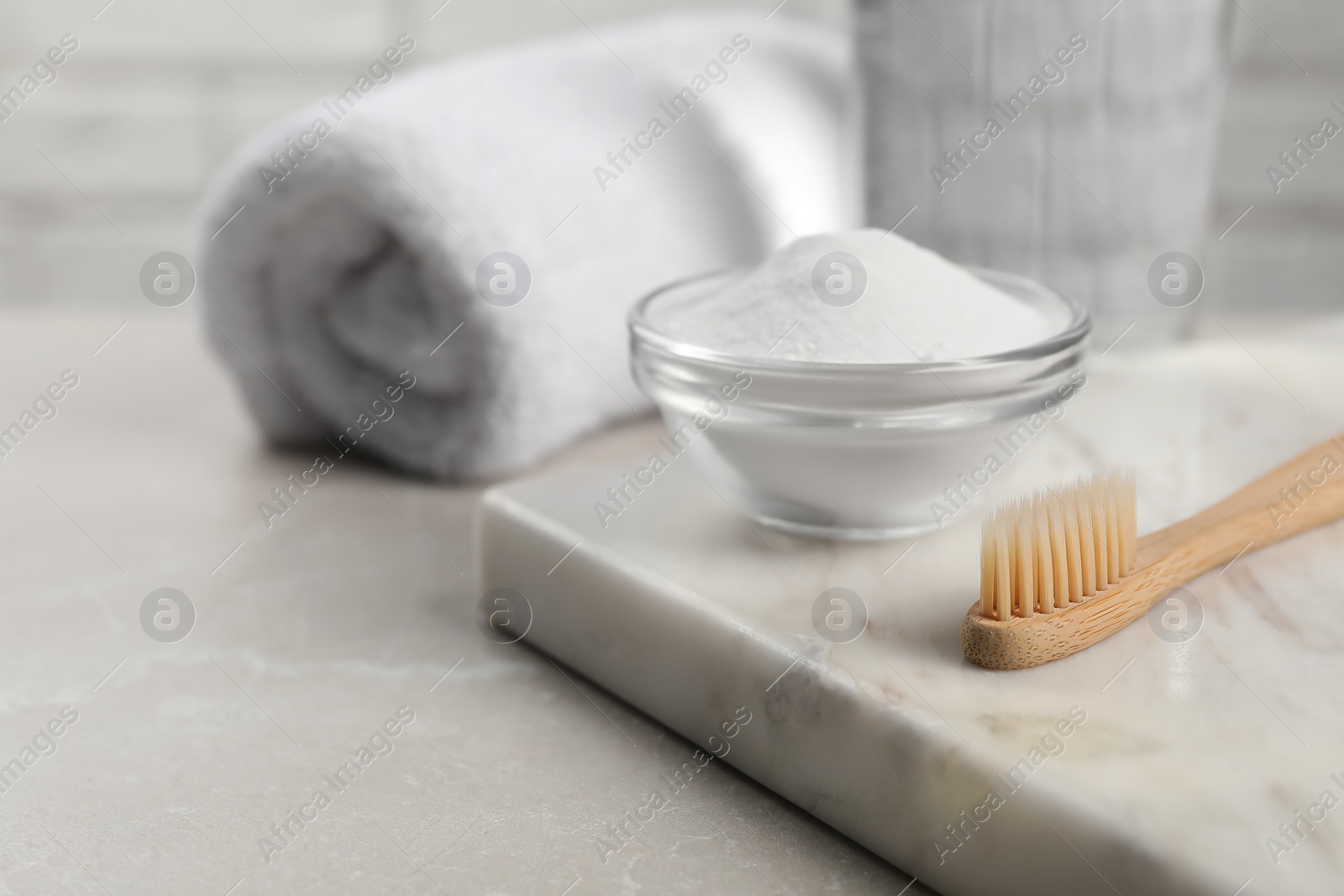 Photo of Bamboo toothbrush and glass bowl of baking soda on light table, space for text