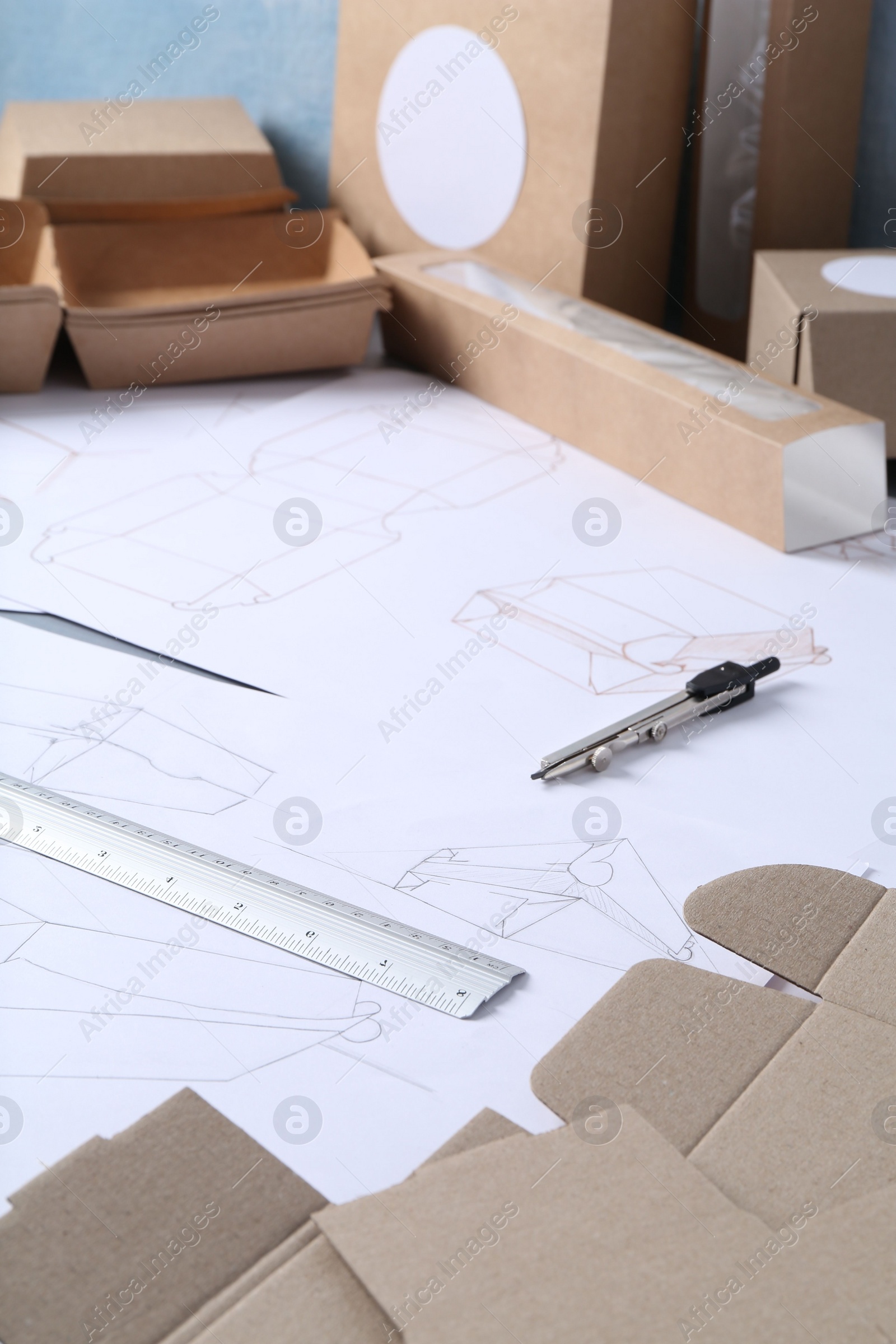 Photo of Creating packaging design. Drawings, boxes and stationery on table, closeup