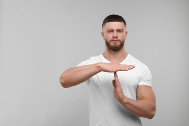 Photo of Man showing time out gesture on light grey background. Space for text